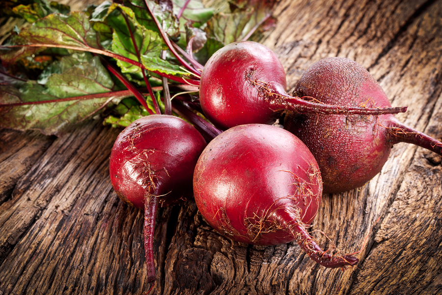 A bunch of beets sitting on top of a wooden table.