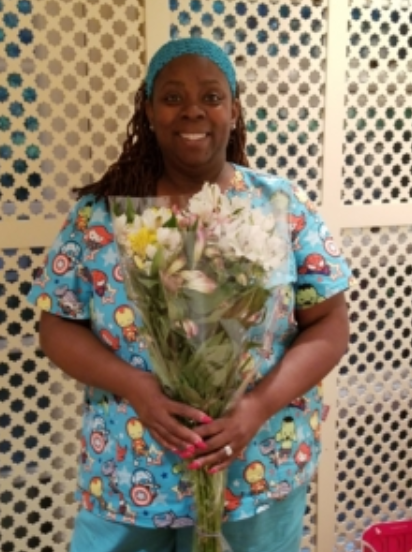 A woman in blue scrubs holding flowers.
