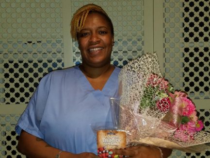 A woman holding some food and flowers