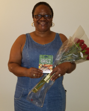 A woman holding flowers and smiling for the camera.