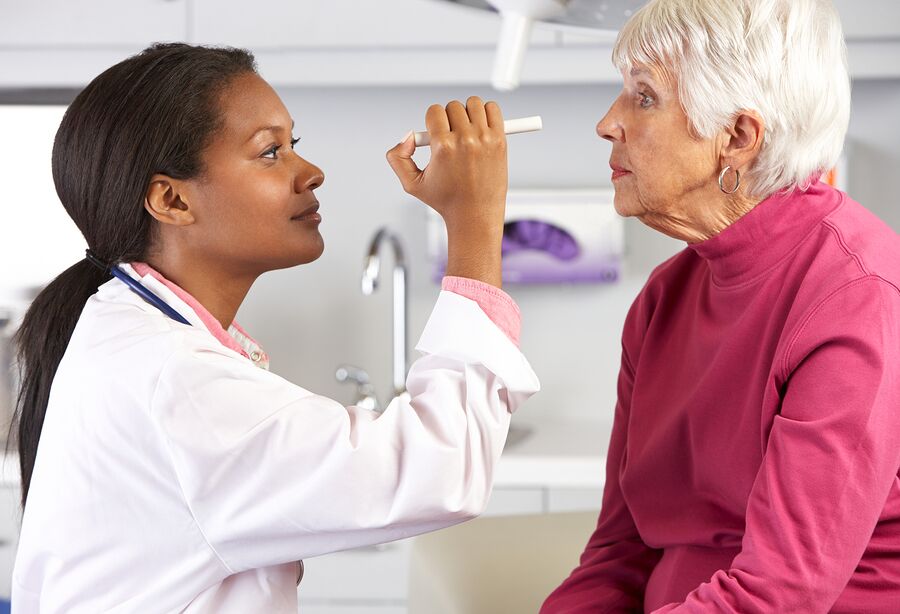 A doctor checking the eye of an older woman.