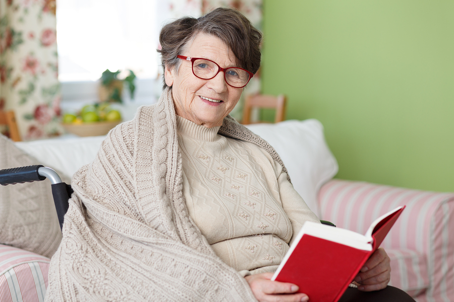 A woman sitting on the couch reading a book.