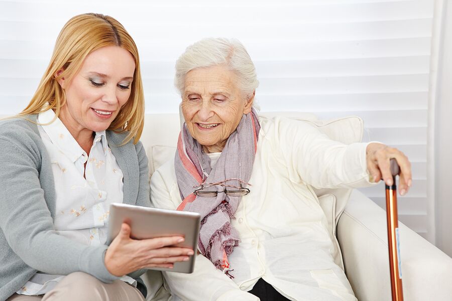 A woman and an old lady looking at a tablet.