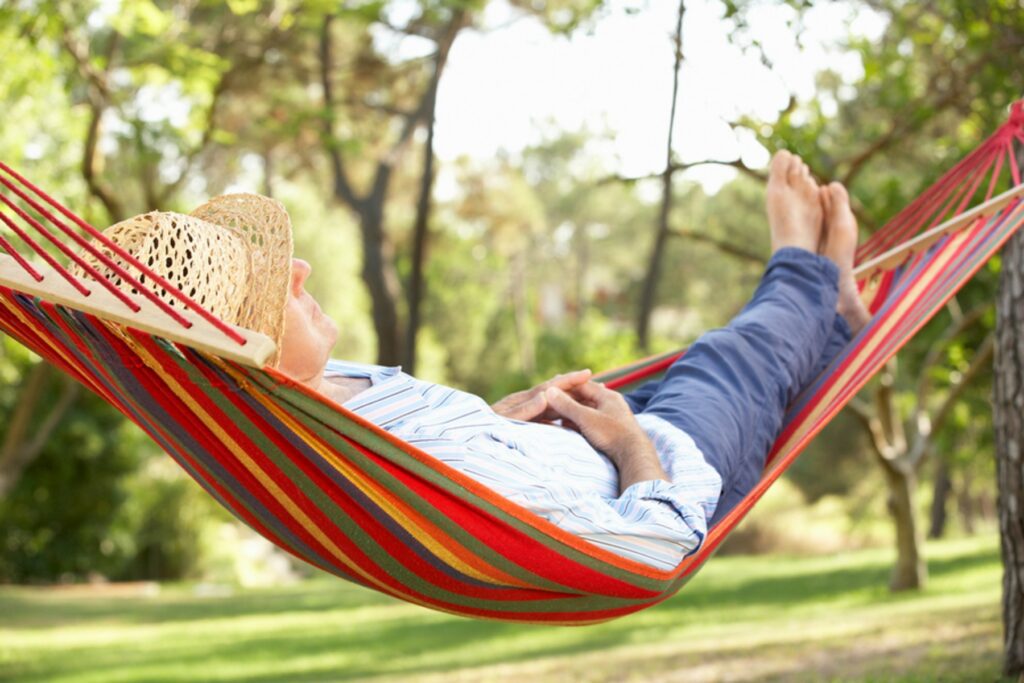 A person laying in a hammock with their feet up.