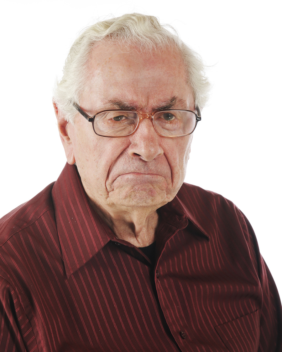 An older man with glasses is frowning.