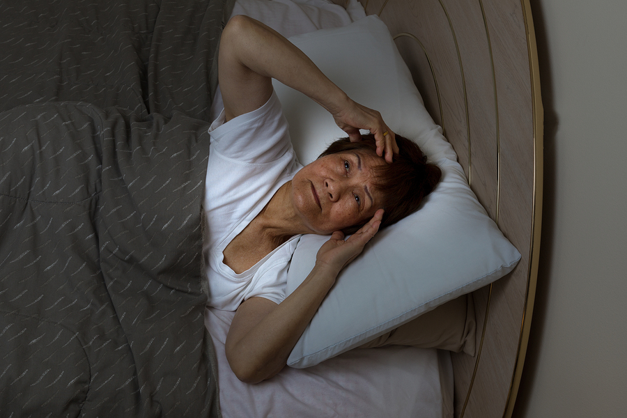 A woman laying in bed with her head on pillows.