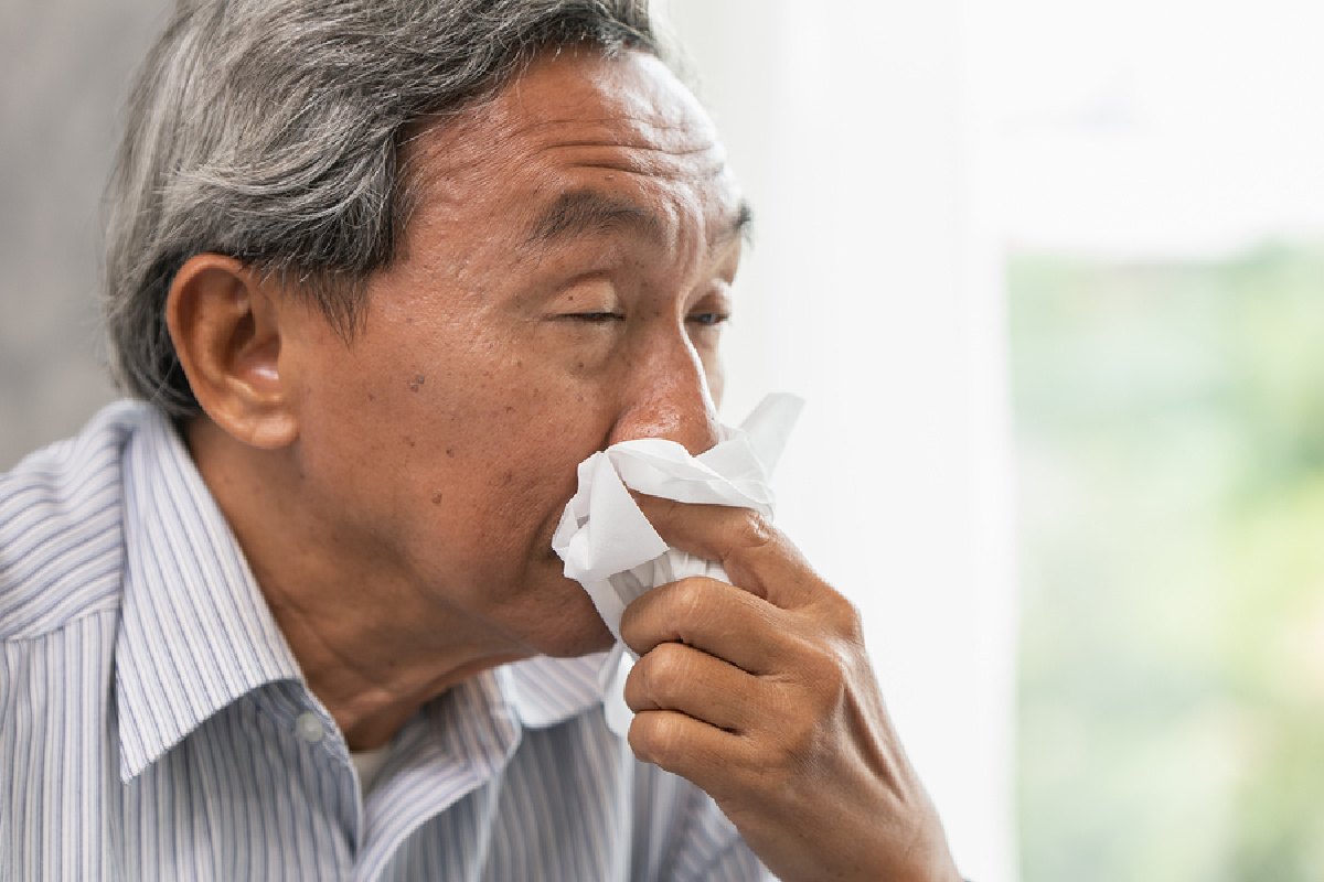 A man with a tissue blowing his nose.