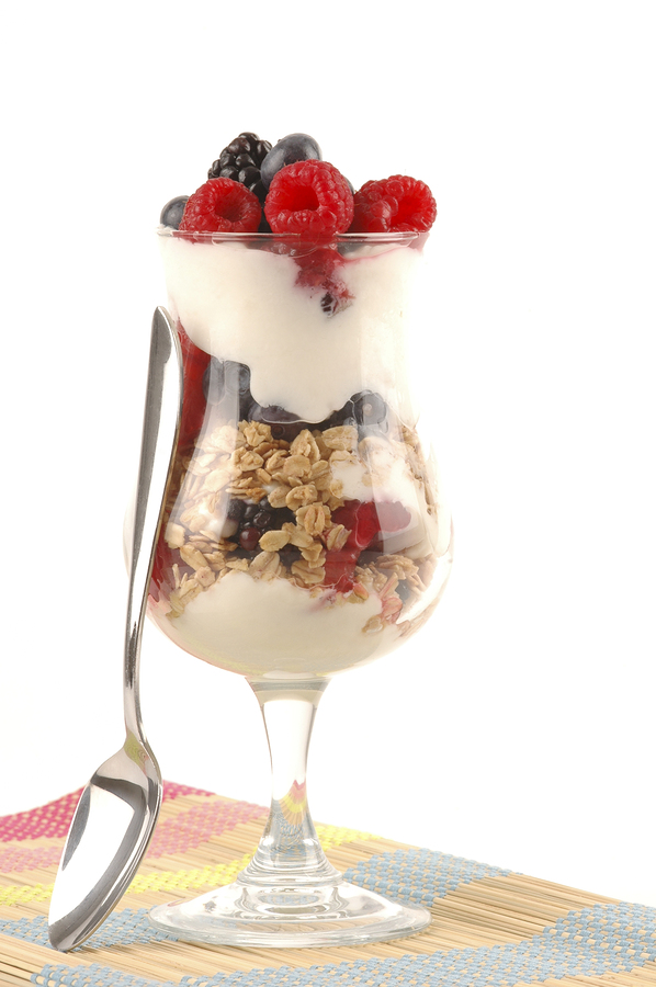 A glass of yogurt with granola and berries.