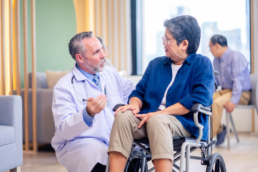 A doctor and patient in a wheelchair talking to each other.