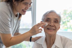 A woman is helping an older person with her ear.