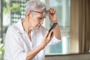 A woman looking at her phone while wearing glasses.