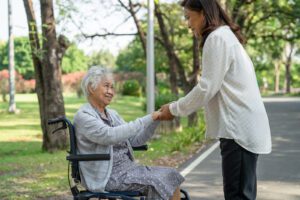 A woman in a wheelchair shaking hands with an older person.