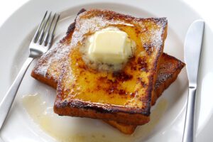 A plate of french toast with butter on top.